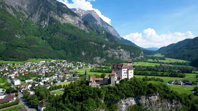 Aerial view of white castle with red roof in Liechtenstein with town below and mountains