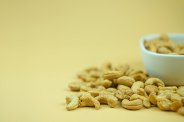 Roasted cashew nuts on a yellow background with copy space.