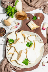 Fresh Pleurotus eryngii mushrooms on wooden background. Raw king oyster eringi with spices and herbs