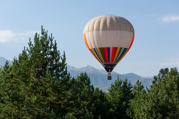 Obraz premium A huge hot air balloon flies over the mountains and pine forest