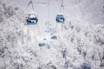 Winter Mountain landscape at the Rosa Khutor ski resort in Sochi, Russia. Cable car cabin over pine...