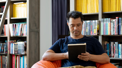 Portrait of Asia man reading book in the library  
