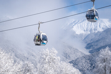 Winter Mountain landscape at the Rosa Khutor ski resort in Sochi, Russia. Cable car cabin over pine...