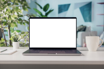 Fototapeta premium Laptop with blank white screen, cozy living room at home, living room interior with cup of steaming coffee