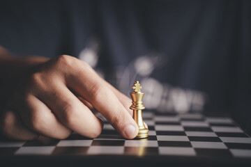 Businessman moving chess piece on chess board game concept for ideas and competition and strategy,...