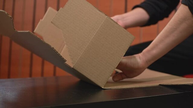 the man himself folds a cardboard box according to the brochure. High-quality FullHD video recording. real-time video