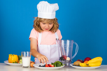 Child chef dressed cook baker apron and chef hat isolated on studio background. Healthy nutrition kids food.