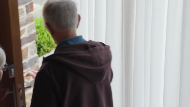 Mature lady opening door for man to leave