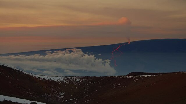 Mauna Loa eruption viewed from Mauna kea Observatory with snow and clouds.