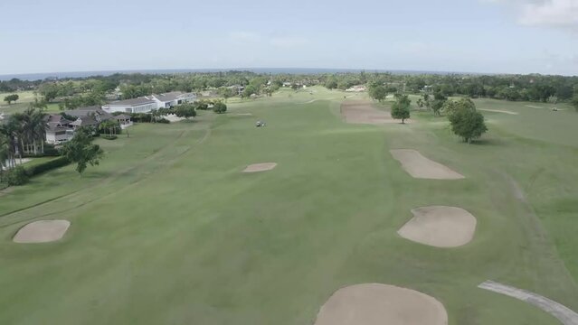 Aerial images of people on a golf course playing sports game in Romana, Dominican republic. Cinematic aerial view of active men playing golf on a sunny summer day.