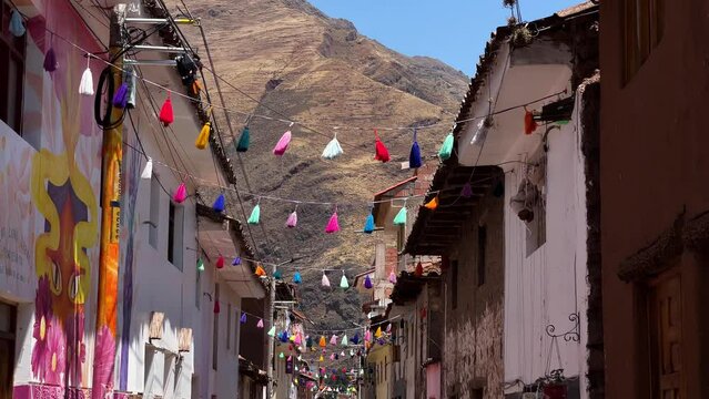 Rainbow colored tassels hang between buildings in Pisac Peru.