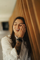 Girl standing at a wood background smiling with a white shirt
