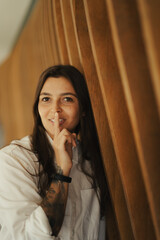 Girl standing at a wood background smiling with a white shirt
