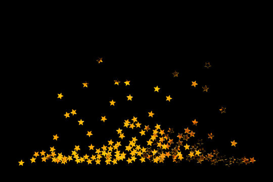 Golden confetty stars on a black background. Design element for a greeting card or party invitation