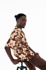 Portrait of african american man leaning back on chair stylish posing looking at camera wearing adorable pretty clothes pants and shirt with funny hairstyle.