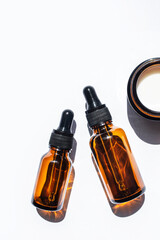 Cosmetic or medical vials of amber glass and a jar of cream on a white background. Top view, space for text. Vertical image.