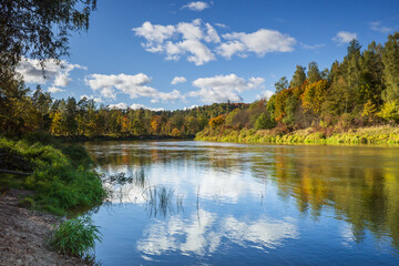 Clouds reflecting in water of Gauja river on sunny autumn day in Turaida