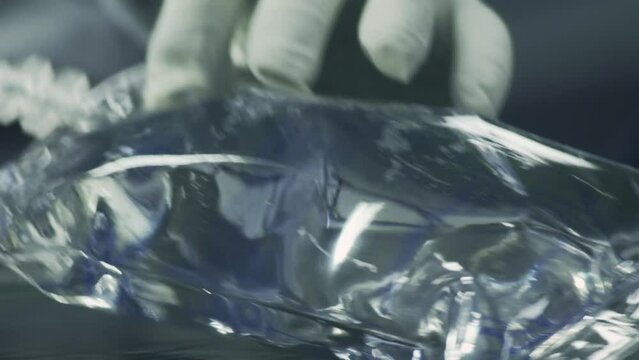 Intravenous infusion liquid Bags traveling Along a conveyor. Hand reaches out and takes the solution bags one by one.Production Line. Production of Physical Solutions. Manufacturing Facility. Close up