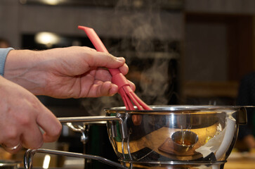 Cooking process: whisking sauce in a saucepan with rising steam