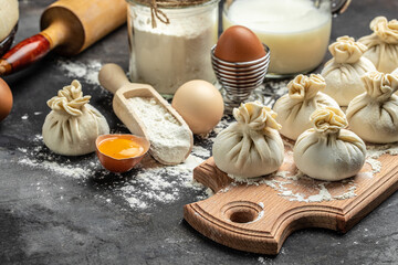Raw Khinkali with meat on a wooden board. semi-finished products dumplings cooking khinkali on a dark background. Georgian dumplings