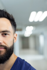 Obraz premium Vertical half portrait of bearded caucasian male healthcare worker in hospital corridor, copy space