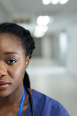 Vertical half face portrait of african american female doctor in hospital corridor, copy space