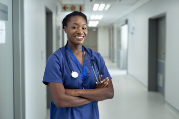 Portrait of smiling african american female doctor in hospital corridor, copy space