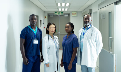 Portrait of diverse group of four doctors and healthcare workers in hospital corridor