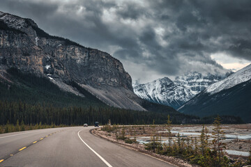 Road trip car driving on highway with moody sky on rocky mountains in Banff national park