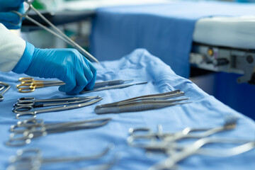 Gloved hand of surgical tech placing tools on table in operating theatre, with copy space