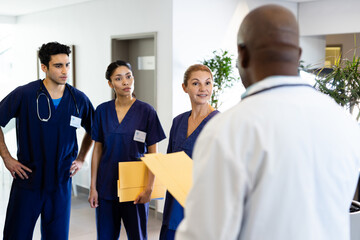 Diverse group of male and female doctors discussing in hospital corridor