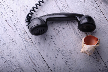 Symbolic composition from a tube of a vintage black phone next to a beautiful sea shell. Long...