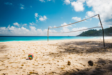 Volleyball net on tropical beach with blue sky. Beach volleyball court with an ocean background. colored ball on the sand. Summer sport concept