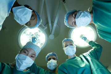 Patient pov of diverse group of female and male surgeons in operating theatre during surgery