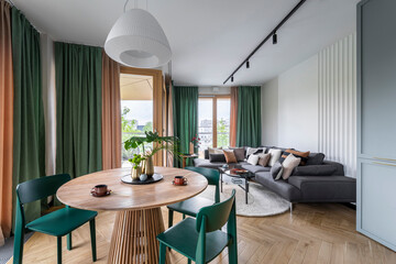 Creative composition of living room interior with dinning room, round table, green chairs, modern...