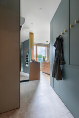 Creative composition of entryway with blue wall, big mirror, gold hangers, cooker hood, gray wall,...