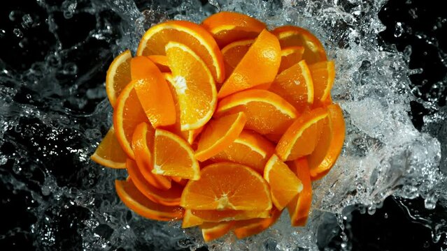 Super Slow Motion Shot of Fresh Orange Cuts and Water Splash Isolated on Black at 1000fps.