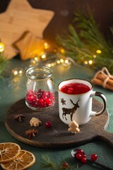 Spicy cranberry tea in two white mugs on a wooden board on a concrete green background in Christmas style. Merry Christmas concept.