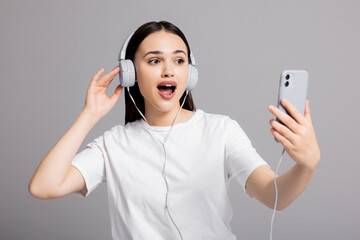 Surprised woman showing different emotions expressions wearing headphones and holding new cellphone and smartphone.