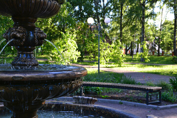 ancient fountain in the park with bench and trees on background, close-up 