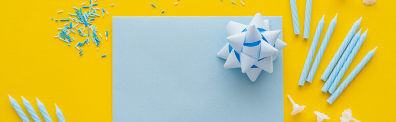 Top view of empty greeting card with candles and sprinkles on yellow background, banner.
