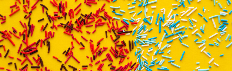Fototapeta na wymiar Top view of red and blue sprinkles on yellow background, banner.