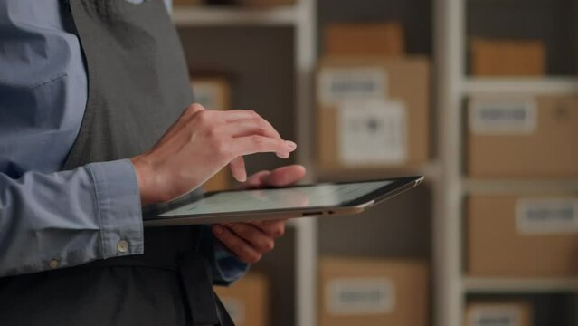 Warehouse database in electronic tablet worker employee holding an electronic tablet looks into a bright screen entering data into virtual tables, Transport company manager in the process of work
