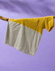 Tshirt hanging on branch and copy space on purple background