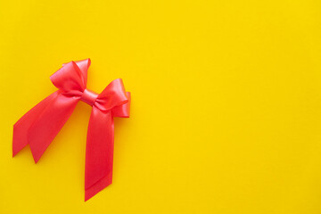 Top view of red bow with copy space on yellow background