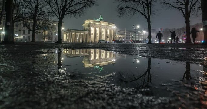 Brandenburger Tor und Reflexion in einer Pfütze nach Regen am Abend in Berlin.