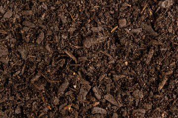 Full frame of dark rich peat soil and bark pieces