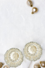 New Year white sparkling wine in glass, two glasses champagne,   christmas balls on fake fur white background, trend beige aesthetic layout, new year party or holiday concept. Top view