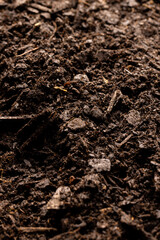Vertical image, full frame of dark rich peat soil and bark pieces