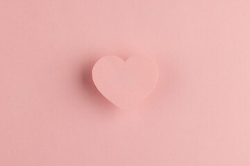Elevated pink heart shape and shadow on pink background with copy space